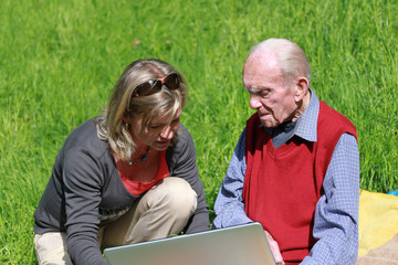 Großvater und Enkelin arbeiten mit Laptop im Grünen