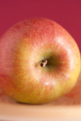 Roter Apfel mit rotem Hintergrund auf Holzteller