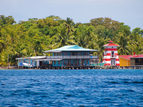 Stilt house over the sea with a lighthouse and tropical vegetation, Caribbean, Bocas del toro, Carenero island, Panama