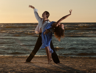 young couple dancing tango on the beach
