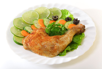 Fried chicken leg on with a lemon and greens