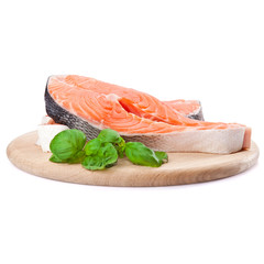 Salmon steak red fish decorated with basil on the kitchen board.