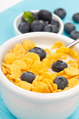 bowl of cornflakes with milk and blueberries