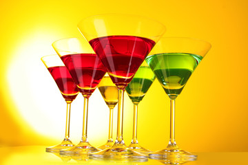 a few glasses of alcoholic drinks in a yellow-brown background
