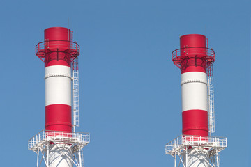 Two industrial smoke pipes over blue sky