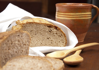 fresh bread with cup of milk and wooden spoons