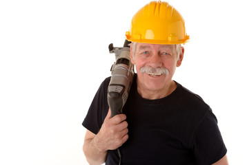 Älterer Arbeiter mit Helm und Bohrmaschine