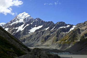 Fototapeta premium New Zealand Mt Cook with snow covered peak blue sky and large lake at the foot of the mountain range.