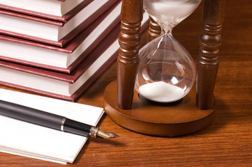 Hourglasses and book on a wooden table