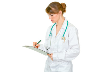 Concentrated medical female doctor making notes in document