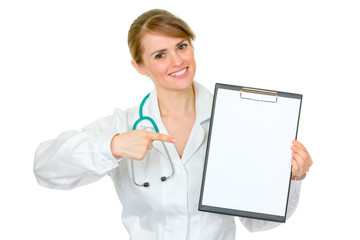 Smiling medical female doctor pointing on blank clipboard