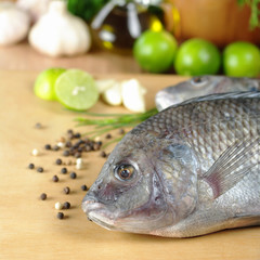 Raw fish called Tilapia surrounded by seasoning