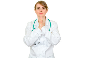 Fototapeta premium Young medical doctor woman praying for success isolated