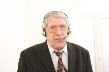 Old businessman with headset  in a call conference