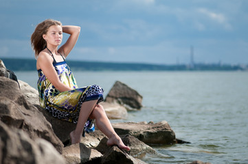 sad woman in dress sitting on rock