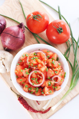 Salsa in a bowl on a wooden board and ingredients