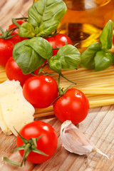 pasta, olive oil and tomatoes on the wood background
