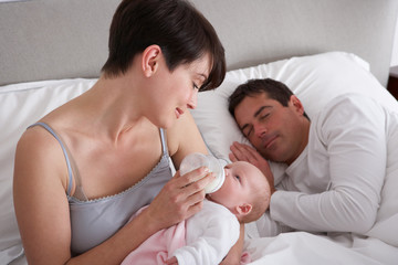 Obraz na płótnie Canvas Mother Feeding Newborn Baby In Bed At Home