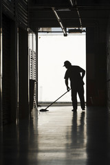 Silhouette of man moping floor
