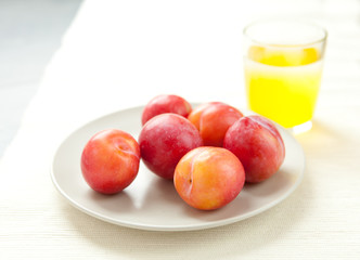 Naklejka na ściany i meble Fresh plums with a glass of juice