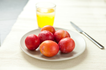 Fresh plums with a glass of juice
