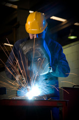 Worker making sparks while welding steel. - obrazy, fototapety, plakaty