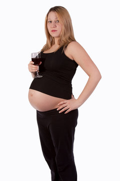 woman showing pregnant belly while holding a glass wine