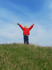 Fototapeta premium The boy is raising his hands against the blue sky