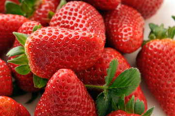 a pile of ripe strawberries with leaves