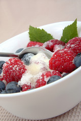 fresh raspberries and berry with cream and sugar on a bowl