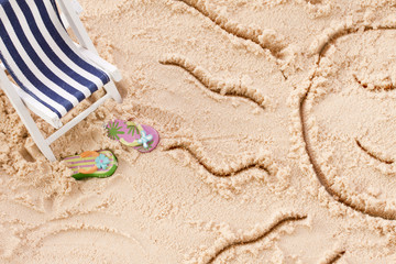 Holiday items on sand with happy sun face