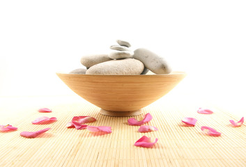 A spa composition of petals, white stones and a ceramic bowl
