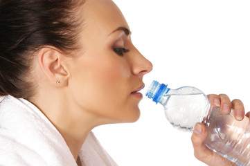 A young and sporty brunette woman is drinking fresh water