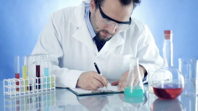 Scientist in laboratory writing in notepad