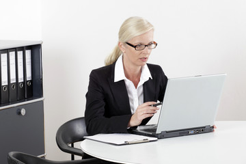 Frau am Schreibtisch mit Laptop erstaunt