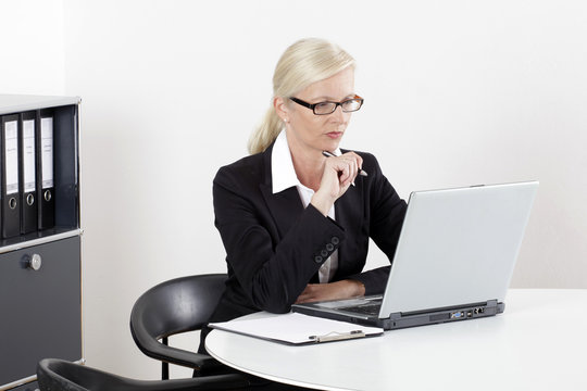 Frau am Schreibtisch mit Laptop im Businessoutfit