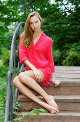 beautiful woman in a red dress sitting on the bridge