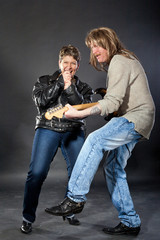 couple acting as rock band with electric guitar
