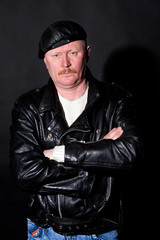 Middle-aged male dressed in leather posing as biker in studio