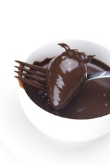 melted chocolate in a cup, fork and strawberries isolated on whi