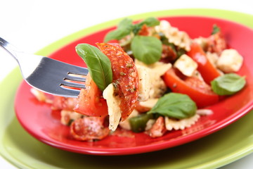 Salad being eaten - farfalle, tomato, salami, mozzarella, basil