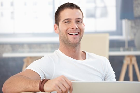 Young man laughing happily at home