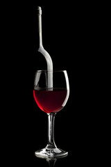 Elegant red wine glass and a wine bottle in black background