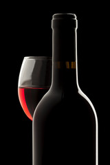 Elegant red wine bottle and wine glass in a black background