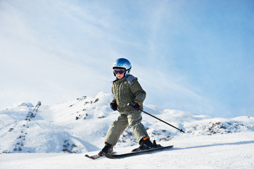 Naklejka na ściany i meble Small child skiing on snow slope