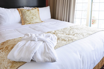 Hotel bed with bathrobe - obrazy, fototapety, plakaty