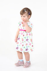 little girl holds a finger in a mouth.