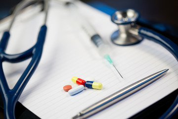 Note pad with stethoscope and pen along with serynge and capsul