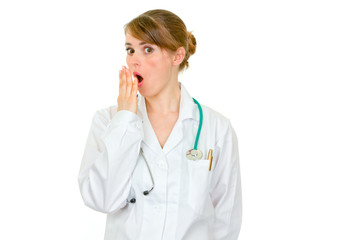 Shocked female medical doctor holding her hand near mouth