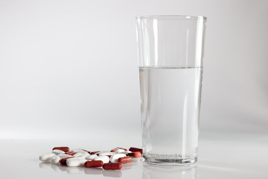 Tabletten mit einem Glas frischen Wasser